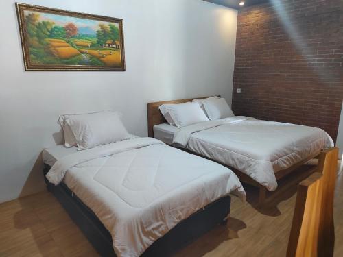 a room with two beds and a painting on the wall at Kampoeng Sekuro in Jepara