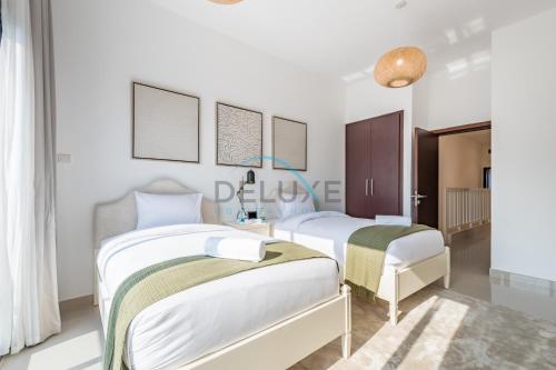 two beds in a room with white walls at Elegant 4BR Villa with Assistant Room in Al Dana Island, Sharm, Fujairah by Deluxe Holiday Homes in Fujairah