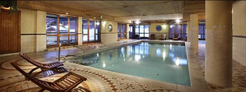 une grande piscine avec deux chaises dans un bâtiment dans l'établissement ARC 2000, Appartement 3 chambres, 10 personnes, à Arc 2000