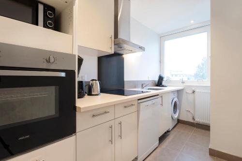 une cuisine avec des armoires blanches et un appareil noir dans l'établissement La Résidence du Général, à Nancy