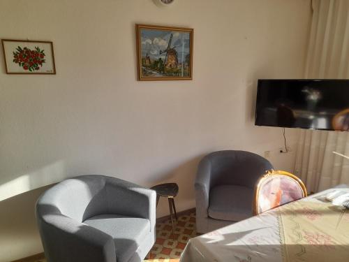 a room with two chairs and a bed and a tv at Friendly Philoxenia in Xanthi