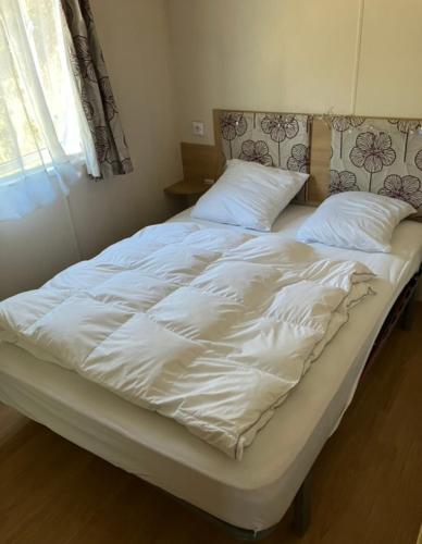 un grand lit blanc avec des draps et des oreillers blancs dans l'établissement Ana et guigui, à Morbier