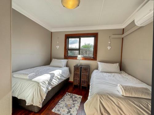 two beds in a small room with a window at Kings 93 Cabins in Tierpoort