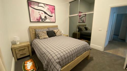 a bedroom with a bed and a night stand and a mirror at Beach Road Hampton Holidays in Melbourne