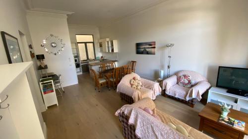 a living room with two chairs and a television at Beach Road Hampton Holidays in Melbourne