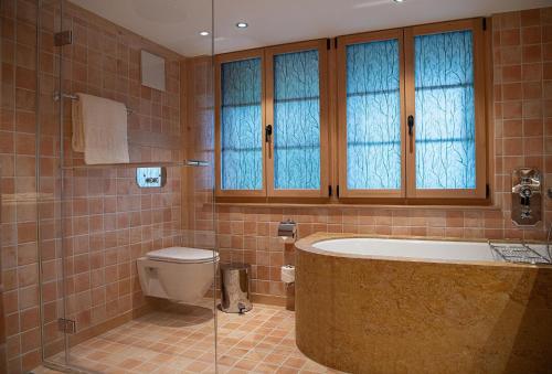 a bathroom with a tub and a toilet at Hotel Olden in Gstaad