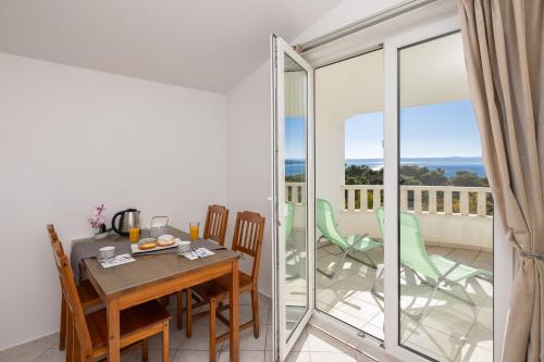 a dining room with a table and chairs and a balcony at Apartments POLARIS in Baška Voda