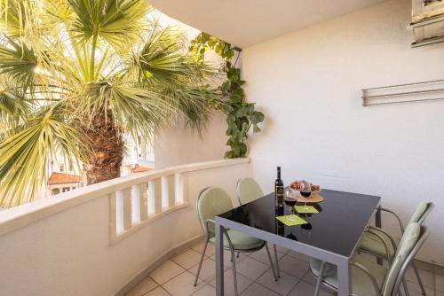 a balcony with a table and chairs and palm trees at Apartments POLARIS in Baška Voda