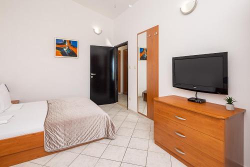 a bedroom with a tv on a dresser with a bed at Apartments POLARIS in Baška Voda