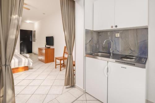 a kitchen with a sink and a room with a bed at Apartments POLARIS in Baška Voda