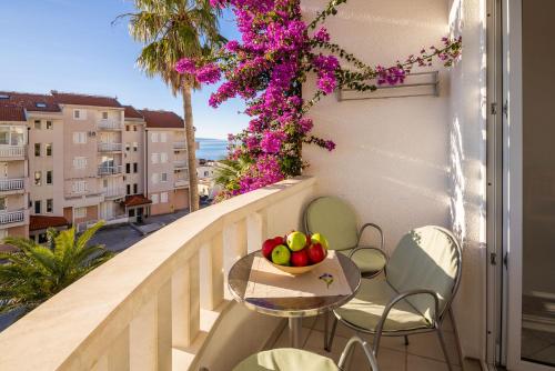 a table and chairs on a balcony with a bowl of fruit at Apartments POLARIS in Baška Voda