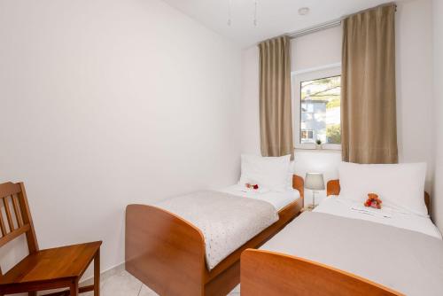 two beds in a room with a window at Apartments POLARIS in Baška Voda