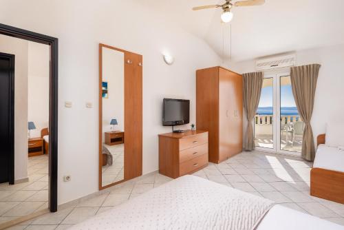 a bedroom with a bed and a tv and a balcony at Apartments POLARIS in Baška Voda