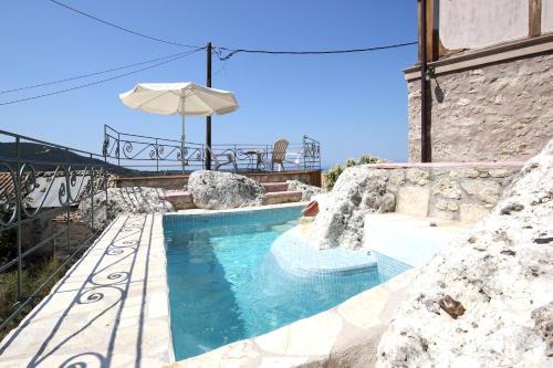 Una piscina con una sombrilla al lado de un edificio. en Gragada House, en Katouna