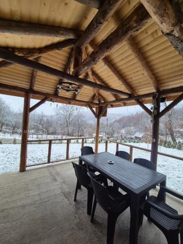 a wooden table and chairs on a covered porch with snow at Cabana AFrame Olanesti in Băile Olăneşti