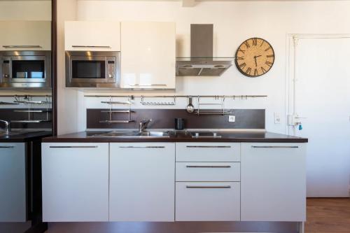 une cuisine avec des placards blancs et une horloge murale dans l'établissement Air-Conditioned Studio Heart of Cannes, à Cannes