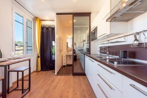 une cuisine avec des armoires blanches et un plancher en bois dans l'établissement Air-Conditioned Studio Heart of Cannes, à Cannes