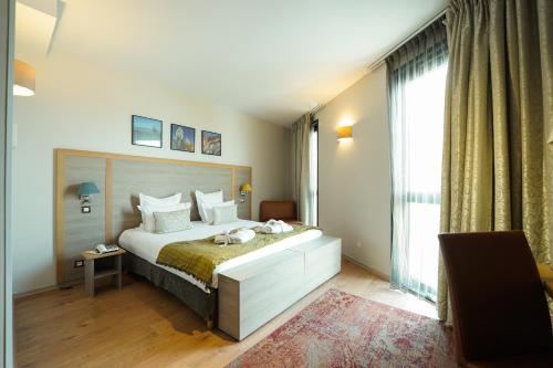 ボルドーにあるHotel Vatel Bordeauxのベッドと大きな窓のある寝室
