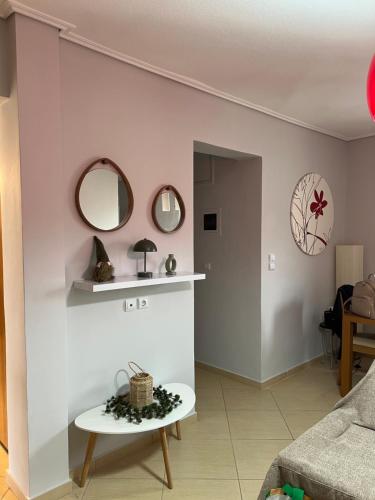 ein Wohnzimmer mit einem Tisch und Spiegeln an der Wand in der Unterkunft 19 Αri in Tríkala