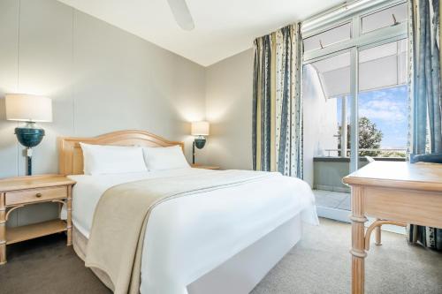 a bedroom with a bed and a desk and a window at Dolphin Beach Hotel Self Catering Apartments in Bloubergstrand