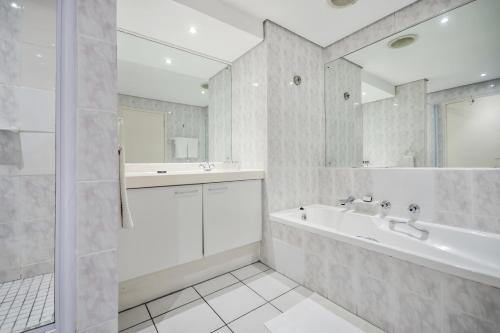 a white bathroom with a tub and a sink at Dolphin Beach Hotel Self Catering Apartments in Bloubergstrand