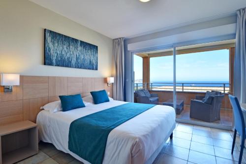 a hotel room with a bed and a balcony at Calvi Résidence, Appart'hôtel in Calvi