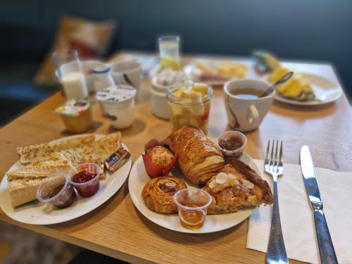 a wooden table topped with plates of breakfast foods at Kyriad Carcassonne - Aéroport in Carcassonne