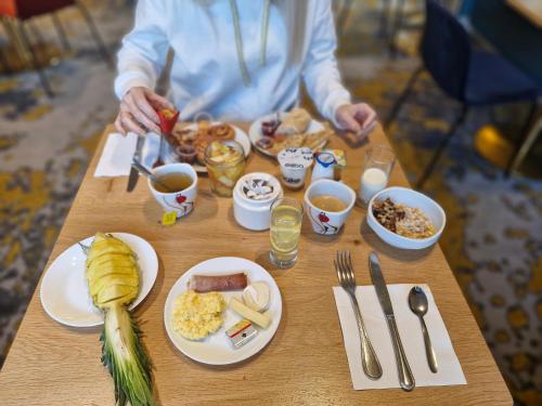 a person sitting at a table with breakfast foods at Kyriad Carcassonne - Aéroport in Carcassonne