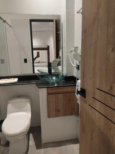 a bathroom with a toilet and a sink with a mirror at Hotel Luna Verde in Doradal