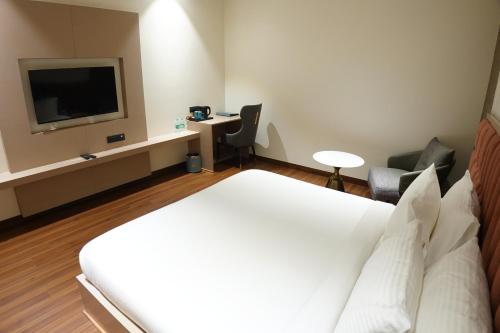 a hotel room with a bed and a flat screen tv at The Pearl Petal in Rohtak