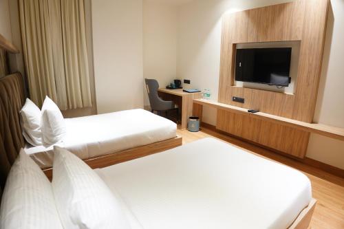 a hotel room with two beds and a flat screen tv at The Pearl Petal in Rohtak