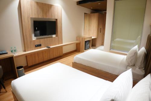 a hotel room with two beds and a flat screen tv at The Pearl Petal in Rohtak