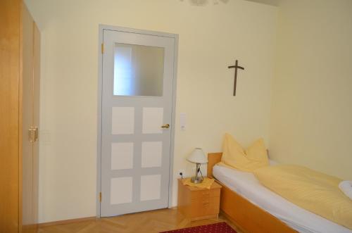 a bedroom with a white door and a cross on the wall at Gästehaus im Priesterseminar Salzburg in Salzburg