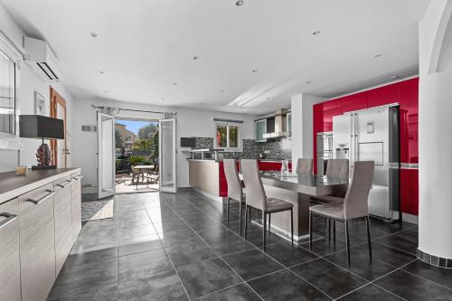 une cuisine avec des placards rouges et une table avec des chaises dans l'établissement Baîeta - Appt climatisé Jacuzzi vue mer, à Menton
