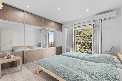 a bedroom with two beds and a large window at Baîeta - Appt climatisé Jacuzzi vue mer in Menton