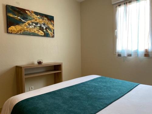 a bedroom with a bed with a blue blanket and a window at Calvi Résidence, Appart'hôtel in Calvi