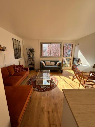 ein Wohnzimmer mit Sofa und Tisch in der Unterkunft Appartement lumineux Mairie des Lilas in Les Lilas