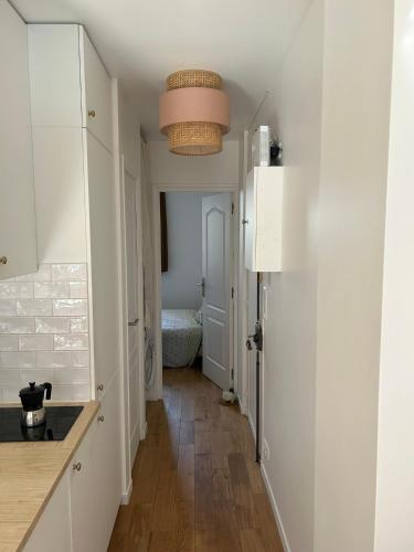 une cuisine avec des placards blancs et un couloir dans l'établissement Appartement lumineux Mairie des Lilas, aux Lilas