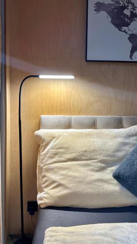 a bed with a white pillow and a lamp next to it at Luxusní apartmán v Praze Klánovicích na zahradě, 20 minut do centra Prahy in Šestajovice