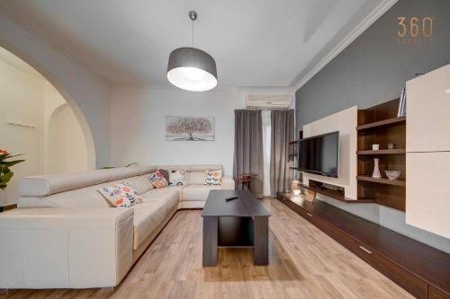 un soggiorno con un divano bianco e una TV di Cosy 3BR home Apt with private balcony in B'Bugia a Birżebbuġa