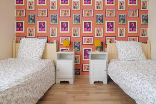 deux lits dans une chambre avec un mur avec des tableaux dans l'établissement Bel appartement 6 personnes - Quartier Arago, à Les Sables-dʼOlonne