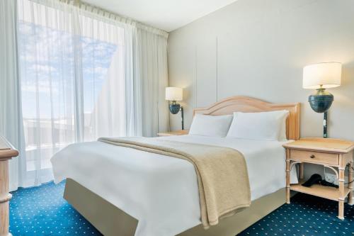 a bedroom with a large white bed and a window at Dolphin Beach Hotel Self Catering Apartments in Bloubergstrand