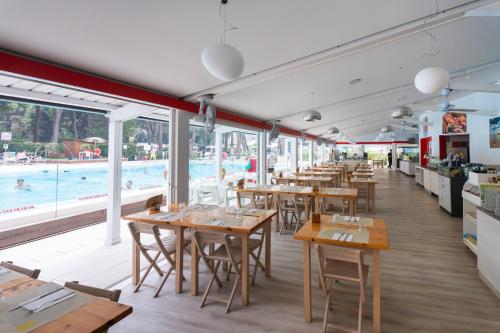 a restaurant with tables and a pool in the background at Club del Sole Jesolo Family Resort in Lido di Jesolo