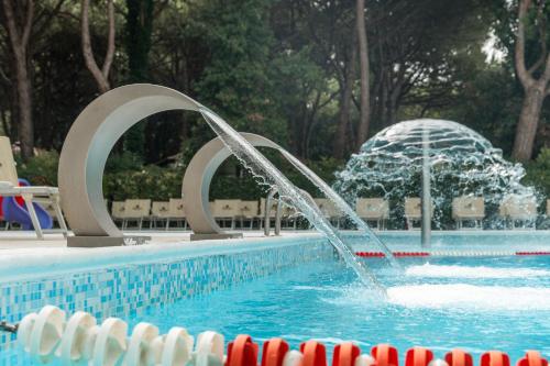 a swimming pool with a fountain in the middle of it at Club del Sole Jesolo Family Resort in Lido di Jesolo