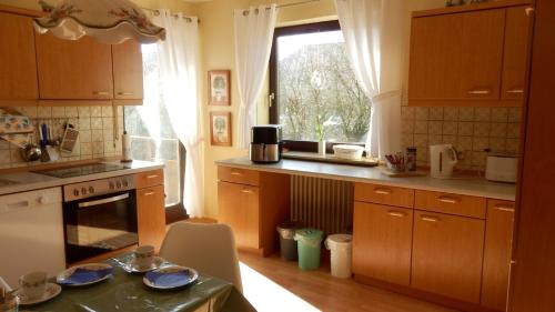 a kitchen with wooden cabinets and a stove and a window at Ferienwohnung Margit in Sulzfeld
