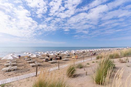 a beach with chairs and umbrellas and the ocean at Club del Sole Jesolo Family Resort in Lido di Jesolo