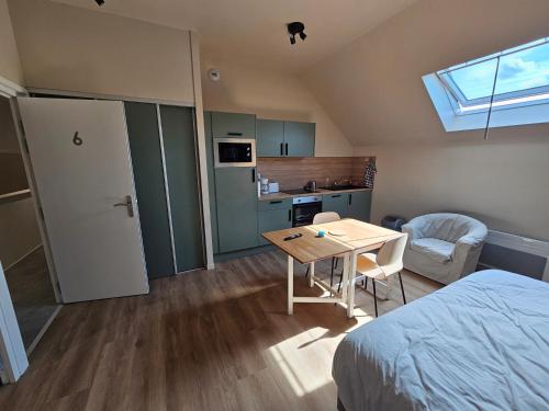 Cette chambre comprend un lit, une table et une cuisine. dans l'établissement Les Gîtes du Moulin des Loups studios 3 et 6, à Saint-Amand-les-Eaux