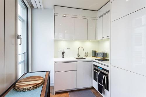 a small kitchen with white cabinets and a table at Idyllic Covent Garden Flat in London