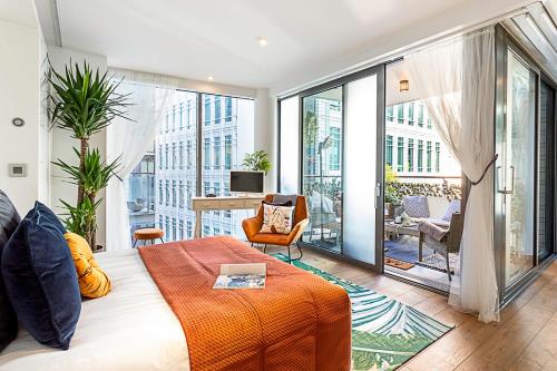 a bedroom with a bed and a balcony with a desk at Idyllic Covent Garden Flat in London