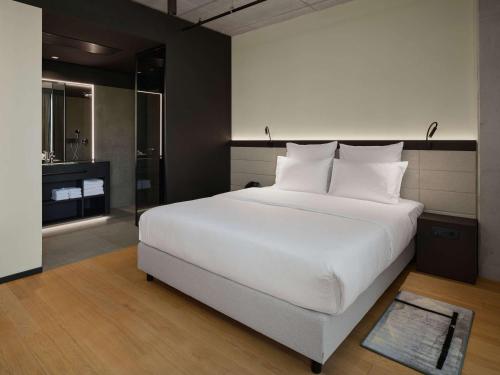 a bedroom with a large white bed and a bathroom at Pullman Zagreb in Zagreb